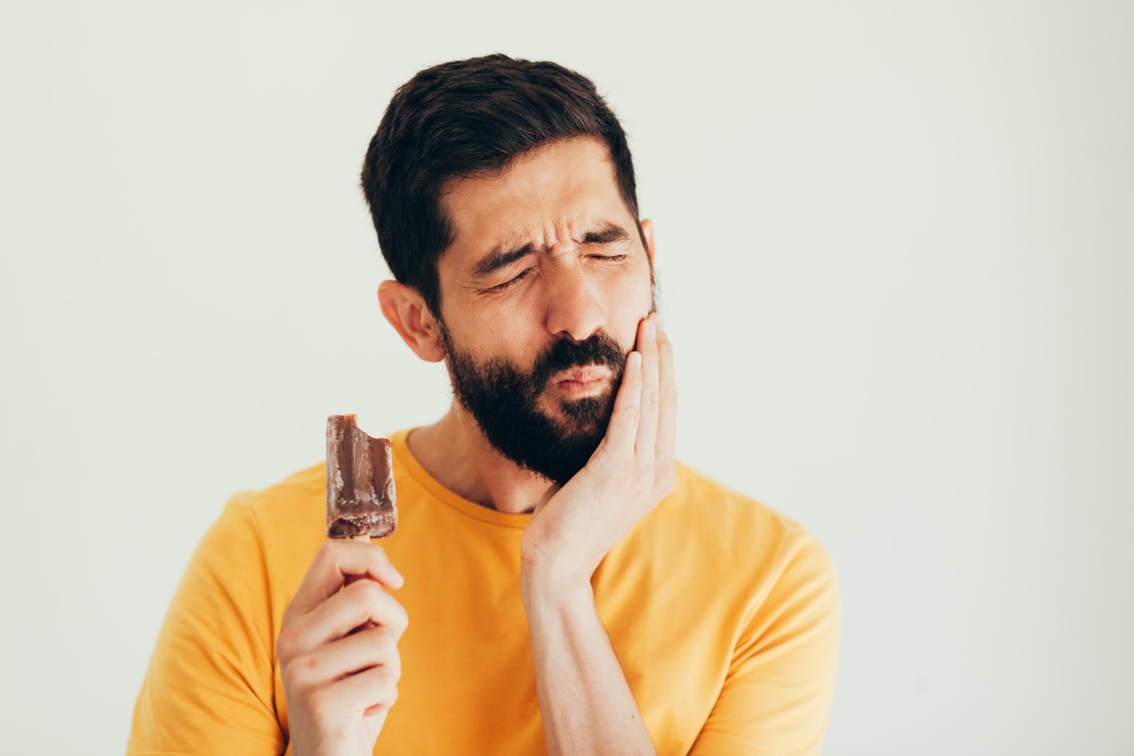 Man,Have,Sensitive,Teeth,With,Ice,On,White,Background Najčastejšie sa vyskytuje citlivosť zubov na chlad, čo vyvoláva kontakt so studeným jedlom ako je zmrzlina